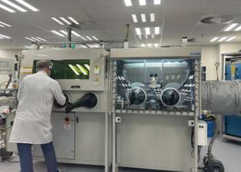 Técnico trabajando en una sala limpia en Jerusalén con una cabina de manipulación sellada para ensamblar componentes de microondas y radiofrecuencia