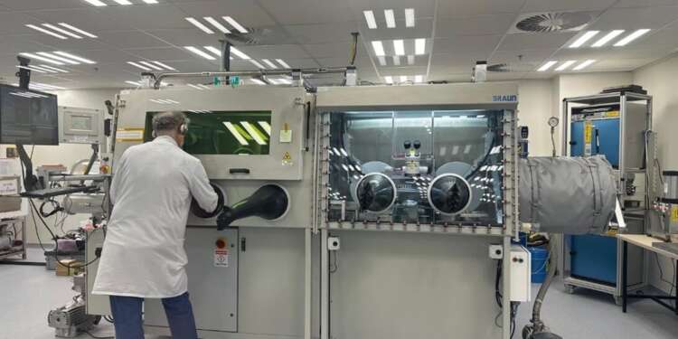 Técnico trabajando en una sala limpia en Jerusalén con una cabina de manipulación sellada para ensamblar componentes de microondas y radiofrecuencia