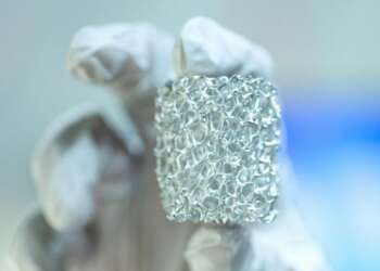 Muestra de material metálico poroso sostenida en laboratorio — revolución de los agujeros